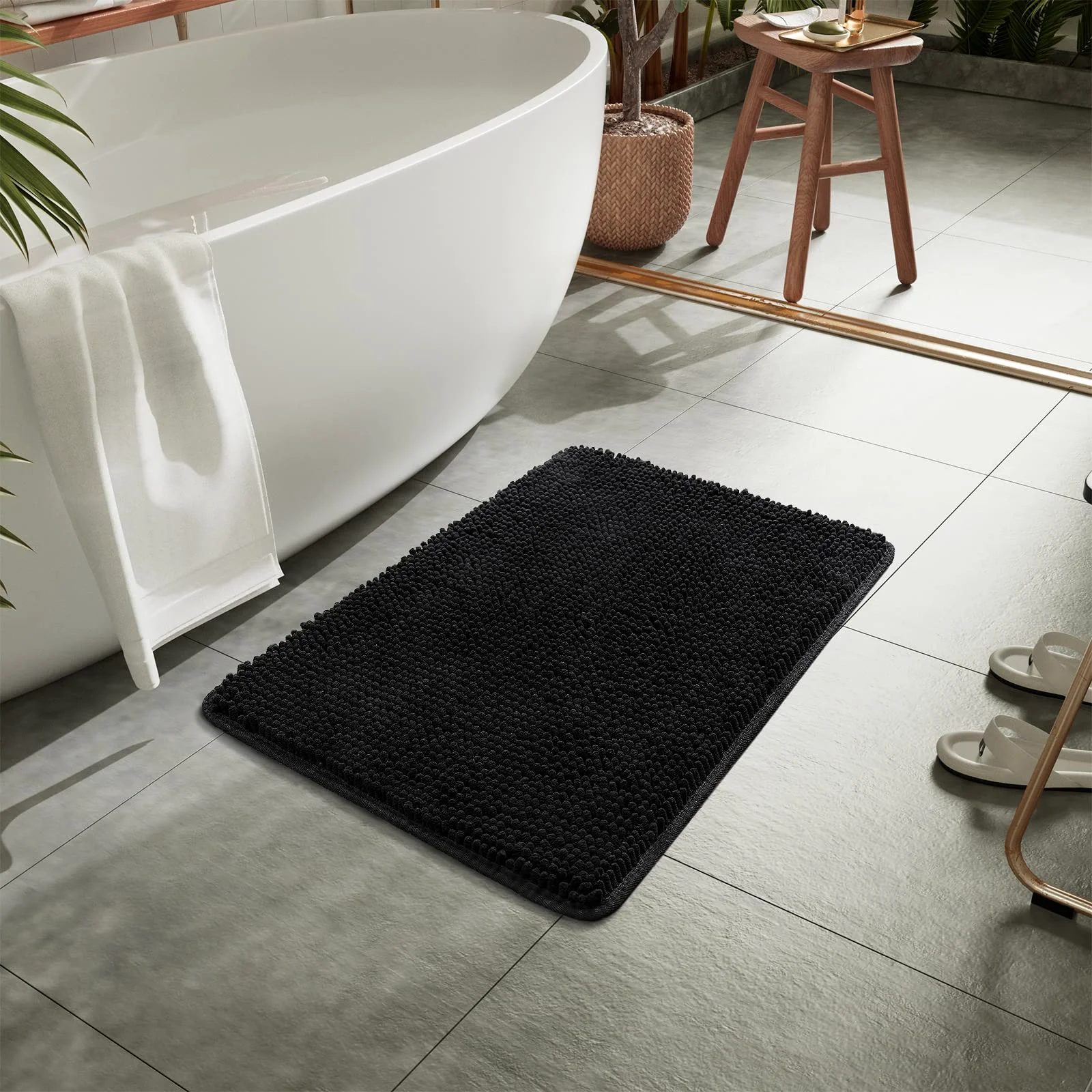 Black chenille next to a white tub: the contrast that shows where the mat actually is.